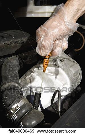 Removing oil dipstick to check motor oil View Large Photo Image Stock Photo - Removing oil dipstick to check motor oil. Fotosearch