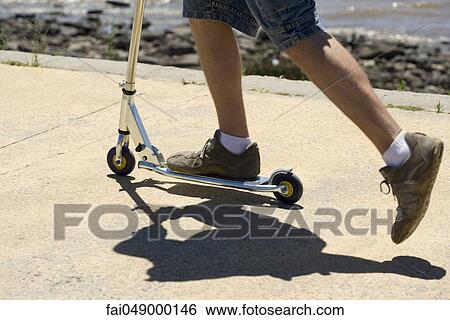 Stock Photograph - Riding push scooter at seaside. Fotosearch