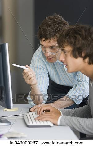 Teacher assisting student with computer assignment View Large Photo Image Stock Photo - Teacher assisting student with computer assignment. Fotosearch