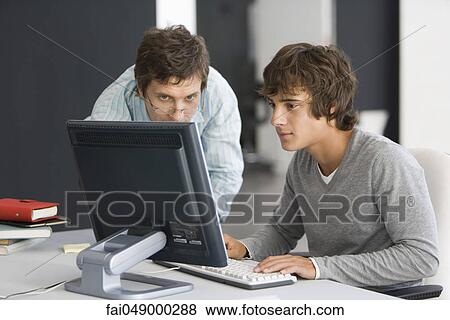Teacher assisting student with computer assignment View Large Photo Image Stock Photo - Teacher assisting student with computer assignment. Fotosearch