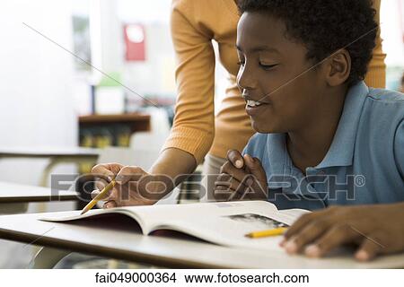 Teacher helping elementary school student with classwork View Large Photo Image Picture - Teacher helping elementary school student with classwork. Fotosearch