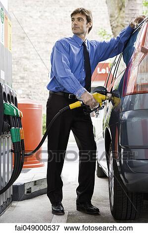 Stock Photo - Well-dressed man refueling vehicle at gas station. Fotosearch
