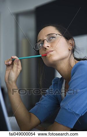 Woman contemplatively looking away with pen in mouth View Large Photo Image Picture - Woman contemplatively looking away with pen in mouth. Fotosearch