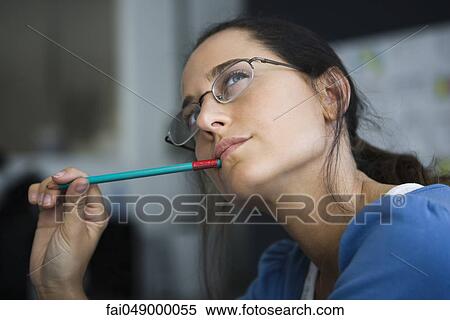 Woman thinking, looking away, pen in mouth View Large Photo Image Stock Photography - Woman thinking, looking away, pen in mouth. Fotosearch