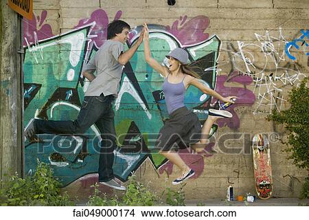 Young couple jumping for high-five View Large Photo Image Picture - Young couple jumping for high-five. Fotosearch