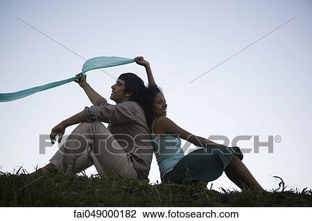 Young couple sitting in grass back to back View Large Photo Image Stock Image - Young couple sitting in grass back to back. Fotosearch