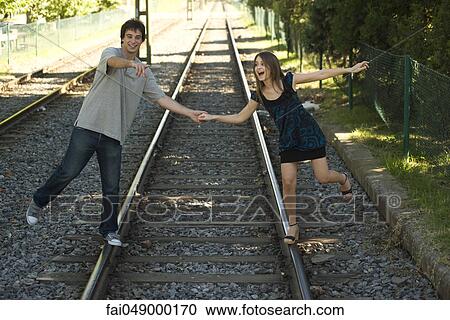 Young couple walking on rail track, holding hands View Large Photo Image Stock Image - Young couple walking on rail track, holding hands. Fotosearch