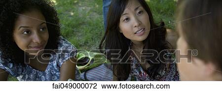 Stock Image - Young friends chatting together outdoors, close-up. Fotosearch