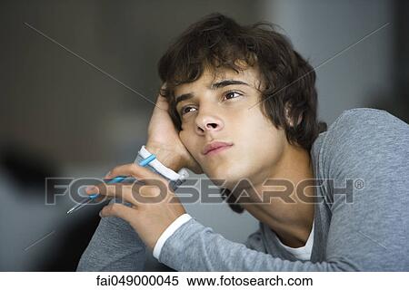 Young man leaning on elbow idly looking away View Large Photo Image Stock Photography - Young man leaning on elbow idly looking away. Fotosearch