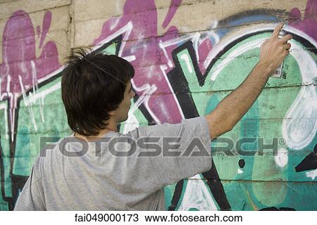 Young man spray painting graffiti mural View Large Photo Image Stock Image - Young man spray painting graffiti mural. Fotosearch