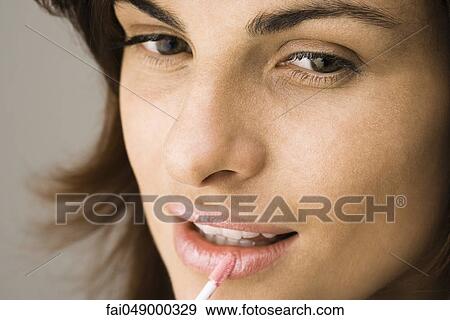 Young woman applying lip-gloss with lip brush View Large Photo Image Stock Photo - Young woman applying lip-gloss with lip brush. Fotosearch