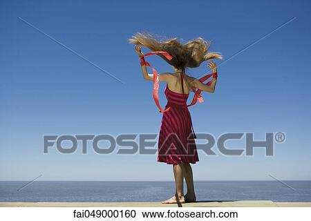 Young woman at beach looking at view, holding streamers in breeze View Large Photo Image Stock Image - Young woman at beach looking at view, holding streamers in breeze. Fotosearch