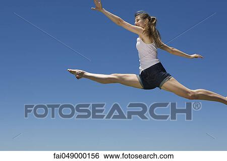 Stock Photograph - Young woman leaping, midair. Fotosearch