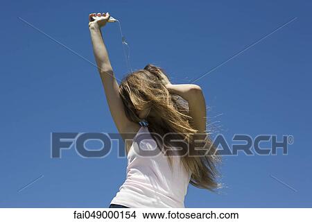Young woman listening to MP3 player, dancing outdoors View Large Photo Image Picture - Young woman listening to MP3 player, dancing outdoors. Fotosearch