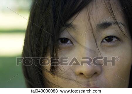 Stock Image - Young woman looking at camera, close-up of face. Fotosearch