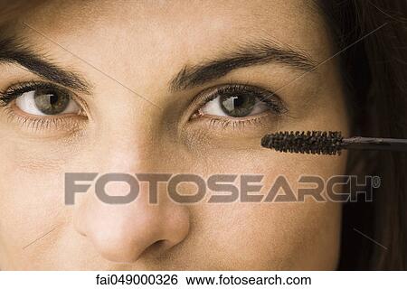 Young woman putting on mascara View Large Photo Image Stock Photograph - Young woman putting on mascara. Fotosearch