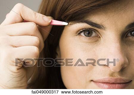 Young woman tweezing eyebrows View Large Photo Image Stock Photo - Young woman tweezing eyebrows. Fotosearch