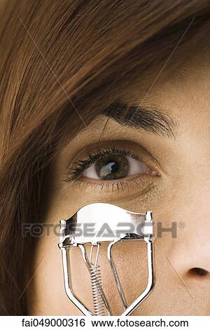 Young woman using eyelash curler View Large Photo Image Stock Photograph - Young woman using eyelash curler. Fotosearch