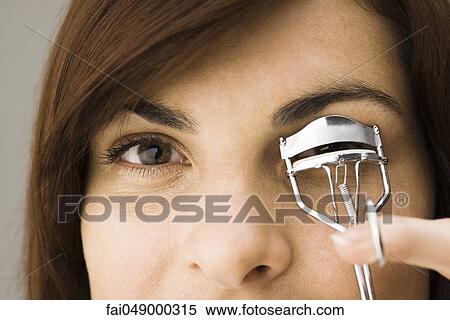 Young woman using eyelash curler View Large Photo Image Stock Photography - Young woman using eyelash curler. Fotosearch