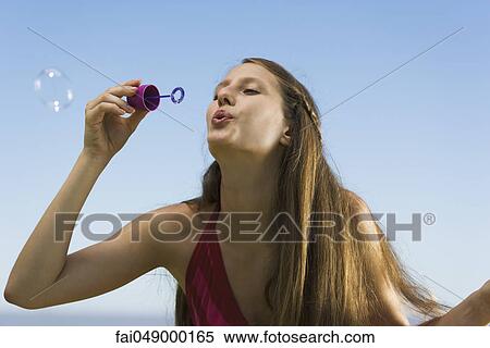 Young woman with bubble wand blowing bubbles View Large Photo Image Stock Photography - Young woman with bubble wand blowing bubbles. Fotosearch