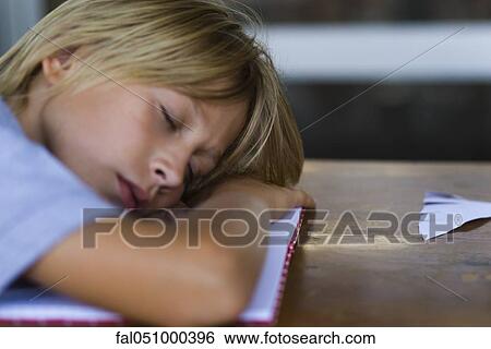 Boy asleep at desk, head resting on arms View Large Photo Image Stock Photograph - Boy asleep at desk, head resting on arms. Fotosearch