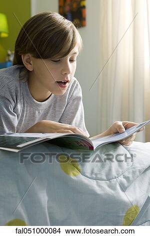 Boy lying on bed reading book View Large Photo Image Picture - Boy lying on bed reading book. Fotosearch