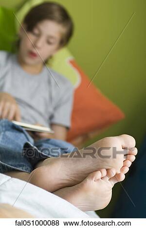 Boy reclining with feet up reading book View Large Photo Image Stock Photo - Boy reclining with feet up reading book. Fotosearch