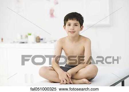 Boy sitting on examining table in doctor's office View Large Photo Image Stock Photography - Boy sitting on examining table in doctor's office. Fotosearch