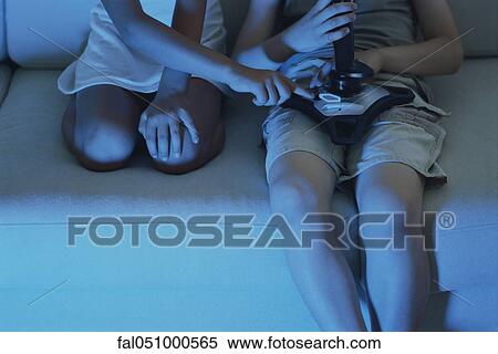 Children playing video game together on sofa, cropped view View Large Photo Image Stock Photography - Children playing video game together on sofa, cropped view. Fotosearch