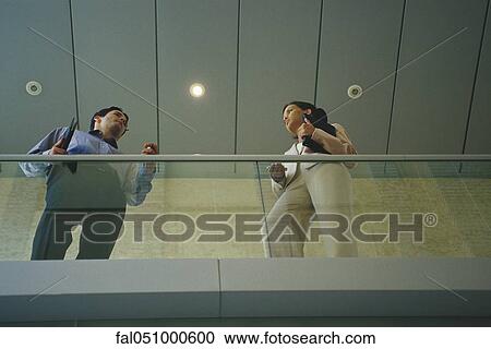 Colleagues talking on balcony, low angle view View Large Photo Image Stock Image - Colleagues talking on balcony, low angle view. Fotosearch