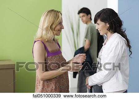 Stock Photo - Concerned mother saying goodbye to teen daughter as she leaves for date with boyfriend. Fotosearch