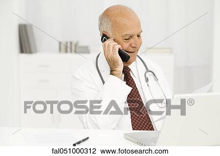 Doctor at desk on phone call View Large Photo Image Stock Image - Doctor at desk on phone call. Fotosearch