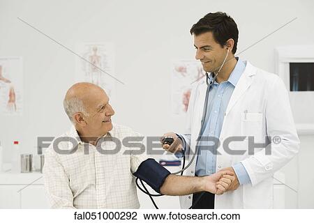 Stock Image - Doctor checking patient's blood pressure. Fotosearch