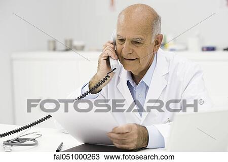 Stock Image - Doctor in office taking phone call. Fotosearch