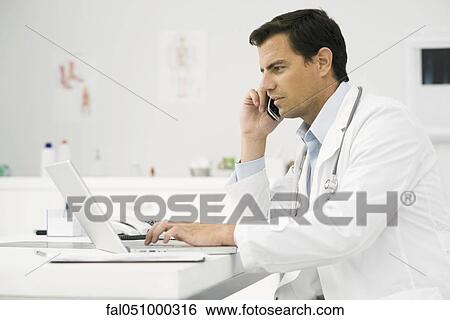 Doctor on phone call using laptop computer View Large Photo Image Stock Photograph - Doctor on phone call using laptop computer. Fotosearch
