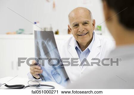 Doctor reviewing patient's x-ray View Large Photo Image Stock Image - Doctor reviewing patient's x-ray. Fotosearch