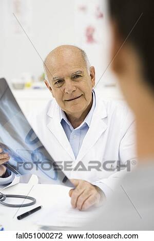 Stock Image - Doctor reviewing patient's x-ray. Fotosearch