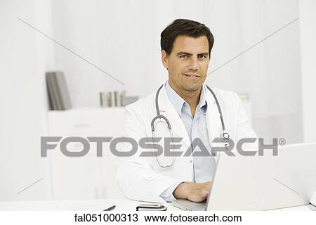 Stock Image - Doctor using laptop computer, portrait. Fotosearch