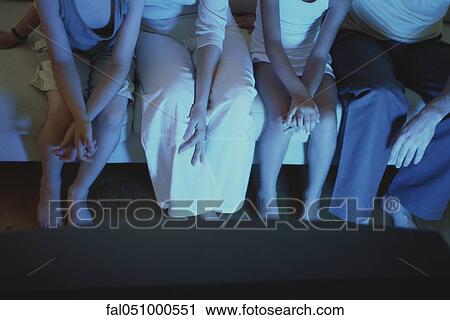 Stock Image - Family sitting together on sofa watching TV, cropped. Fotosearch