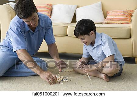 Stock Image - Father and son playing pick up sticks. Fotosearch