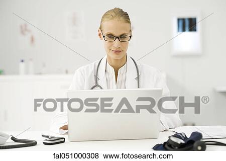 Stock Photo - Female doctor using laptop at desk. Fotosearch