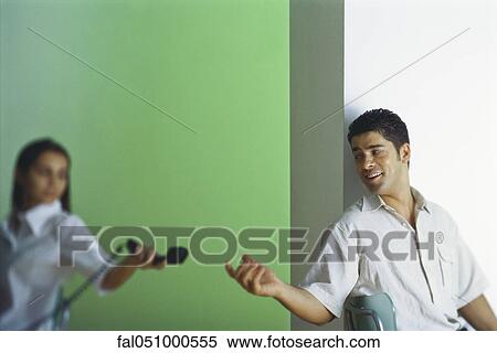 Stock Photography - Female handing man landline phone, focus on man. Fotosearch