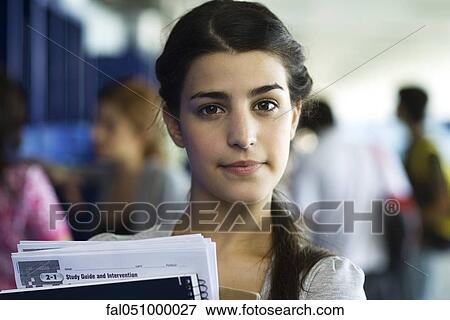 Stock Photo - Female high school student holding books, portrait. Fotosearch