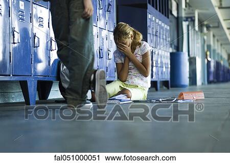 Female junior high student sitting on floor holding head in hands, boy standing smugly nearby View Large Photo Image Stock Image - Female junior high student sitting on floor holding head in hands, boy standing smugly nearby. Fotosearch