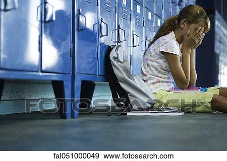 Female junior high student sitting on hall floor near lockers, upset and covering face with hands View Large Photo Image Stock Photo - Female junior high student sitting on hall floor near lockers, upset and covering face with hands. Fotosearch