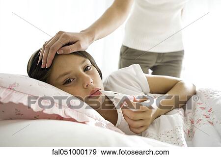 Girl checking temperature with thermometer, mother caressing forehead View Large Photo Image Stock Photo - Girl checking temperature with thermometer, mother caressing forehead. Fotosearch