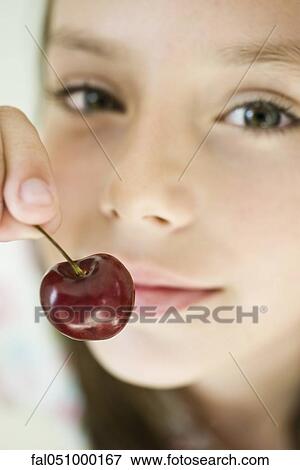 Girl holding up cherry, close-up View Large Photo Image Stock Photo - Girl holding up cherry, close-up. Fotosearch