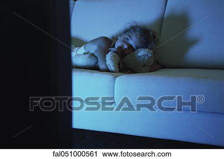 Girl lying on sofa with teddy bear, watching TV View Large Photo Image Stock Image - Girl lying on sofa with teddy bear, watching TV. Fotosearch