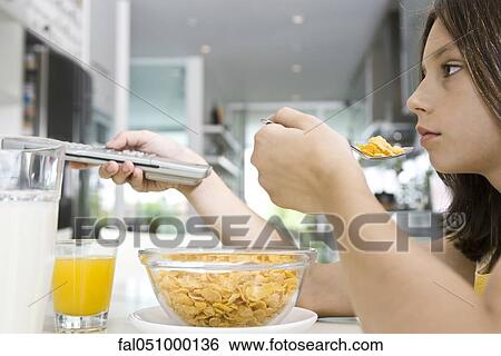 Girl watching television while eating breakfast View Large Photo Image Stock Photograph - Girl watching television while eating breakfast. Fotosearch