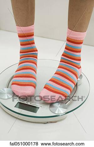 Girl weighing self on bathroom scale, cropped View Large Photo Image Stock Photo - Girl weighing self on bathroom scale, cropped. Fotosearch